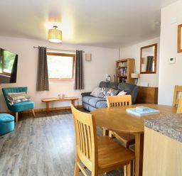 A living room with a sofa and dining table at Dragonfly Lodge Whinburgh near Dereham