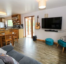 A living room with a dining table and television at Dragonfly Lodge Whinburgh near Dereham