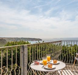 A table with croissants and orange juice on a balcony overlooking the sea at The Lookout in Sennen