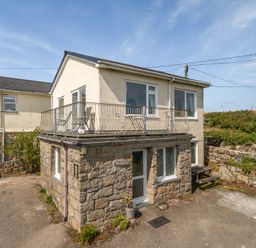 A house with a balcony and stone wall at The Lookout in Sennen