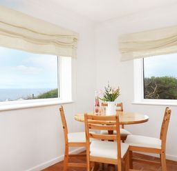 A dining room with a round table and chairs at The Coach House in Sennen near St Just