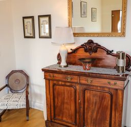 A wooden sideboard with decorative items and a chair in a corner at Millers Lane House in Muff County Donegal