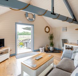 A living room with a sofa and coffee table a television on a stand and a dining table with chairs at The Nook in Louth