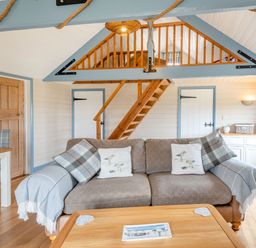 A living room with a sofa, wooden staircase, wooden doors, and a table at The Nook in Louth