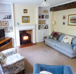 A living room with armchairs a sofa a wood burning stove and bookshelves at Woodside Cottage in Brompton-by-Sawdon