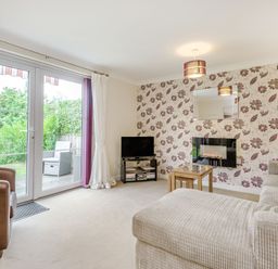 A living room with a sofa a brown armchair a small table a television and glass doors leading outside at Kymin View in Monmouth