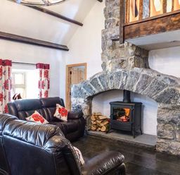 A living room with leather sofas a stone fireplace and floral curtains at The Well House in Kinvara County Galway