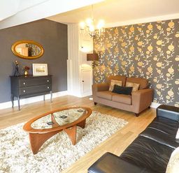 A living room with a brown sofa black sofa wooden coffee table and a patterned wall at High Ridge in Ambleside