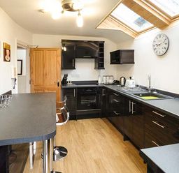 A kitchen with black cabinets a wooden door and skylight windows at High Ridge in Ambleside
