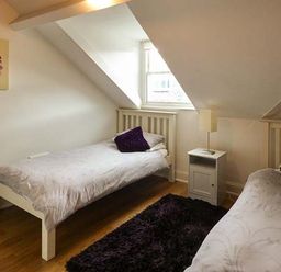 A bedroom with two single beds a nightstand with lamp and a window at High Ridge in Ambleside