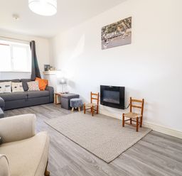 A living room with sofas chairs a television and a wall-mounted fireplace at Sealyons in Fairbourne near Dolgellau