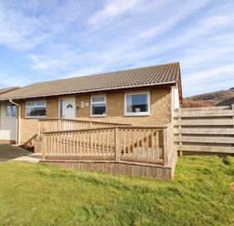 A single story house with a wooden ramp and a lawn at Sealyons Fairbourne near Dolgellau