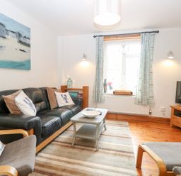 A living room with a sofa, coffee table, and television at Driftwood Cottage in Heacham