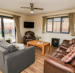 A living room with sofas wooden coffee table tv and patio doors at Caban Nant Ddu in Rhayader