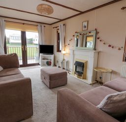 A living room with sofas a television and a fireplace at Roe Deer Lodge Castlewigg near Whithorn