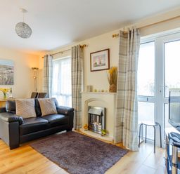 A living room with a black leather sofa a fireplace a television a dining table and chairs at Brook Cottage in Rosecraddoc Lodge near Liskeard