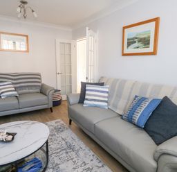 A living room with two grey sofas a round marble coffee table and framed pictures on the wall at Captains Retreat in Christchurch