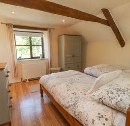 A bedroom with two single beds a wardrobe a chest of drawers a window and wooden beams at Owls Nest in South Molton
