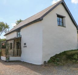A white cottage with a porch and plants outside at Owls Nest in South Molton