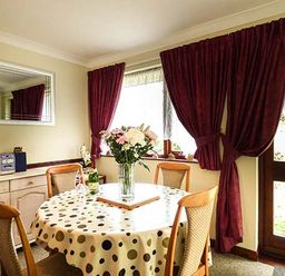 A dining area with a round table covered by a polka dot tablecloth and flowers in a vase at Chy Lowenna Rosecraddoc Holiday Village near Liskeard