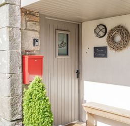 A front door with a small window and a red mailbox next to a stone wall at Berts Cottage in Heights near Appleby-in-Westmorland