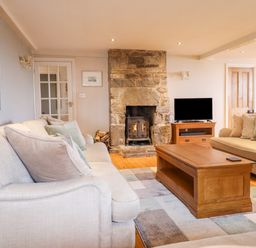 A living room with stone fireplace wooden coffee table and sofas at Is Y Deri in Harlech