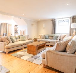 A living room with beige sofas and a wooden coffee table at Is Y Deri in Harlech