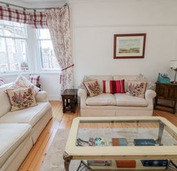 A living room with beige sofas and floral cushions wooden side tables and a glass coffee table at Iona 10 Palace Street East Berwick-upon-Tweed