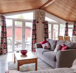 A living room with sofas a wooden table and dining table with chairs at 22 Thirlmere Troutbeck Bridge