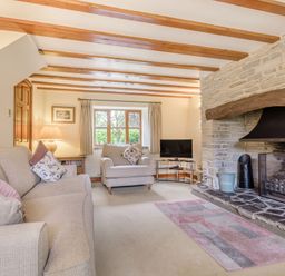 A living room with sofas a stone fireplace wooden beams and a television at West End Barn in Cleeve Prior near Evesham