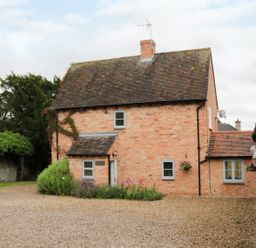 A brick house with a tiled roof and gravel driveway at Pebworth Cottage Pebworth near Stratford-upon-Avon