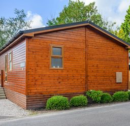 A wooden lodge with a small garden and stairs at Claife View Lodge in Troutbeck Bridge