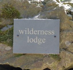 A stone plaque with the words wilderness lodge mounted on a rock with moss