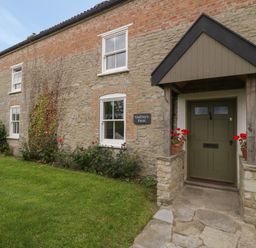 A stone and brick house exterior with a green door and porch at Drover's in Sutton Mallet