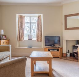 A living room with a window with curtains a television on a stand a coffee table a lamp and sofa at Buttermere Sawrey near Hawkeshead