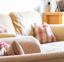 A close up of beige couches with red and beige patterned cushions and a wooden cabinet in the background at Buttermere Sawrey near Hawkeshead