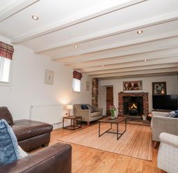 A living room with a fireplace and seating arrangements at Wold Cottage in Hunmanby