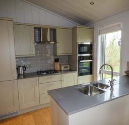 A kitchen with built-in appliances a sink on a countertop and cabinets at Shepherd Lodge Allithwaite near Grange-over-Sands