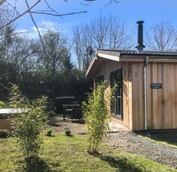 A wooden lodge with patio furniture and a hot tub in a garden at Shepherd Lodge in Allithwaite near Grange-over-Sands