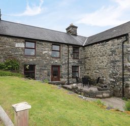 A stone cottage with a patio area and outdoor furniture at Hendy Cottage Llanbedr near Harlech