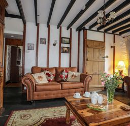 A living room with brown sofas wooden coffee table with tea set and flowers at Hendy Cottage in Llanbedr near Harlech
