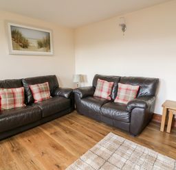 A living room with two leather sofas with cushions wooden floor and a framed picture at Green Cottage in Pant-y-Dwr near Rhayader