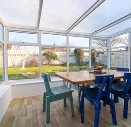 A conservatory with a table and chairs at Merlin's Retreat in Tintagel