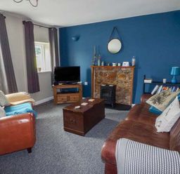A living room with brown leather sofas a wooden chest coffee table and a TV on a wooden stand at Corner Cottage in Reynoldston near Swansea