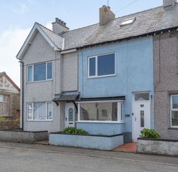 A row of terraced houses with a blue house in the middle on a street at 2 Tregof Terrace in Cemaes Bay