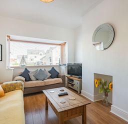 A living room with two sofas a wooden coffee table a television and a decorative mirror at 2 Tregof Terrace in Cemaes Bay