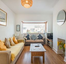 A living room with two sofas a wooden coffee table a television a window with blinds and flowers in a vase at 2 Tregof Terrace in Cemaes Bay