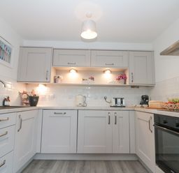 A kitchen with grey cabinets a sink toaster kettle and oven at White Rose Apartment in Filey