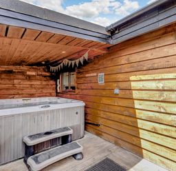 A wooden outdoor hot tub with steps under a wooden roof at Kingfisher Lodge in Brandesburton