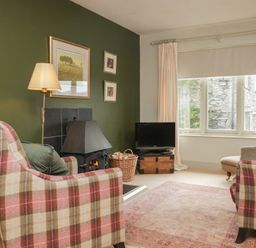 A living room with an armchair, fireplace, and television at Gable End in Coniston near Hawkshead
